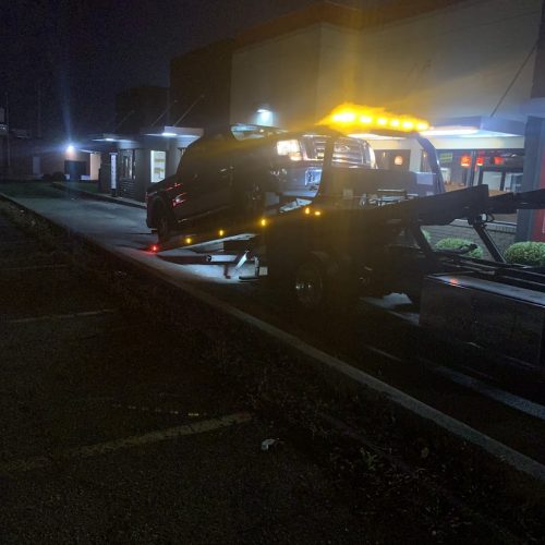 car on the back of a Six Mile Towing tow truck